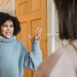 Duas mulheres discutem em um ambiente interno, olhando uma para a outra com expressão de desentendimento.