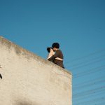 Casal se abraça em um terraço sob o céu azul.