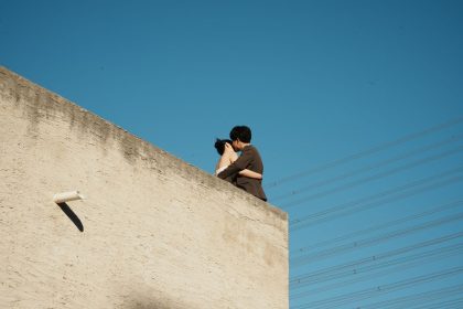 Casal se abraça em um terraço sob o céu azul.